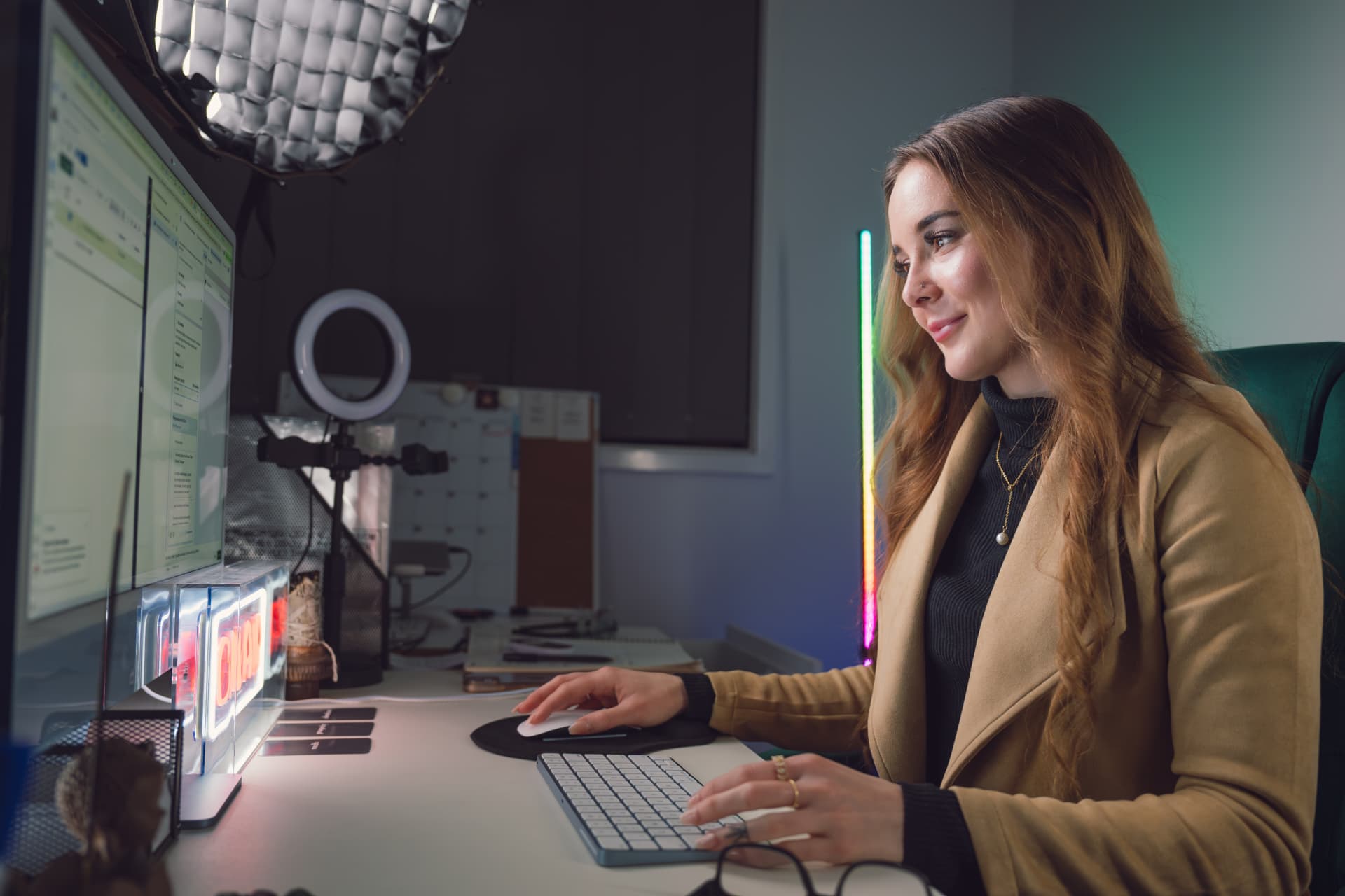 Woman working confidently at a content creator desk with dual monitors and ring light